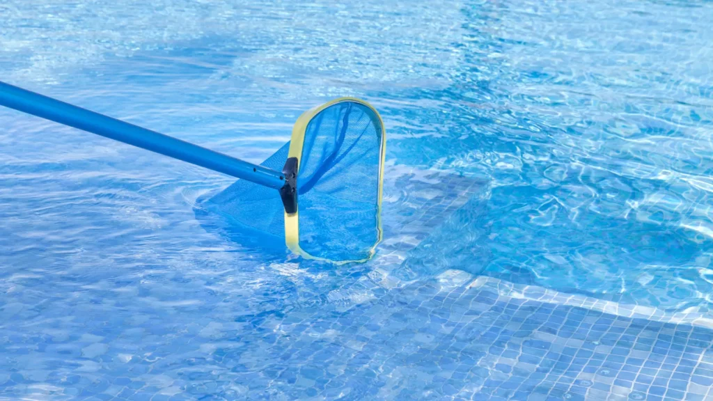 Agent de nettoyage utilisant une épuisette pour nettoyer l'eau d'une piscine